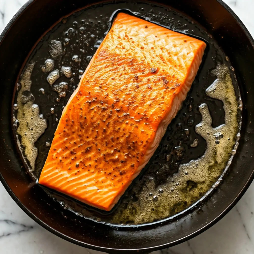 Prep and Cook the Salmon

Pat the salmon fillets dry (because nobody likes soggy salmon).

Add salt, pepper, and a splash of olive oil for seasoning.

In a non-stick skillet heat the oil and butter over medium heat. Cook salmon skin-side down first for crispy goodness, about 3-4 minutes per side, until just opaque in the centre.

Remove from the pan and set aside. Drain the fat from the skillet, but make sure to keep the flavorful browned bits that are stuck to the bottom of the pan (do not wipe the pan clean).