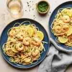 Two blue plates of shrimp scampi pasta with lemon wedges and parsley