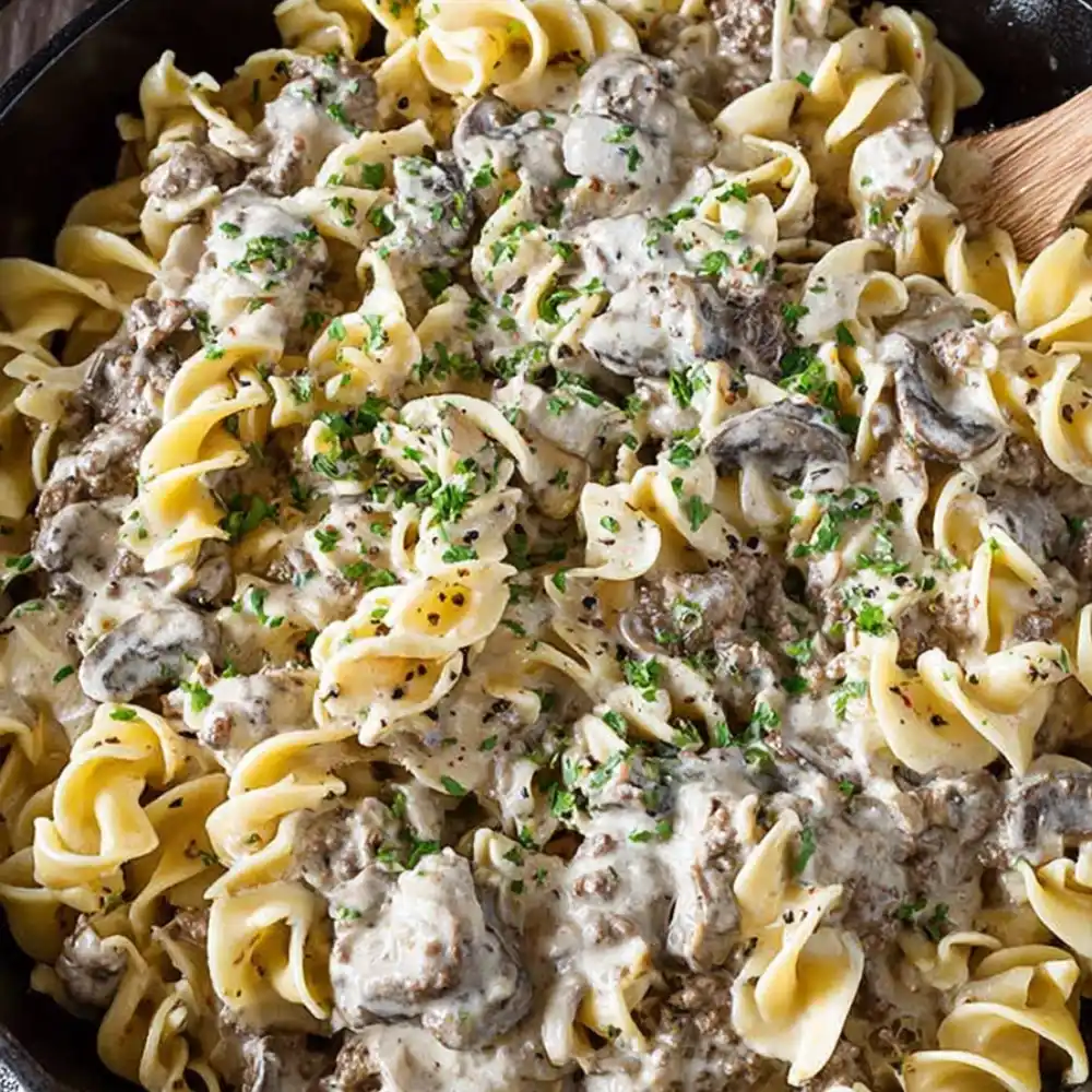 Egg noodles mixed with creamy beef stroganoff sauce and mushrooms in a skillet