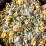 Creamy beef stroganoff Recipe with ground beef and mushrooms served over egg noodles in a skillet