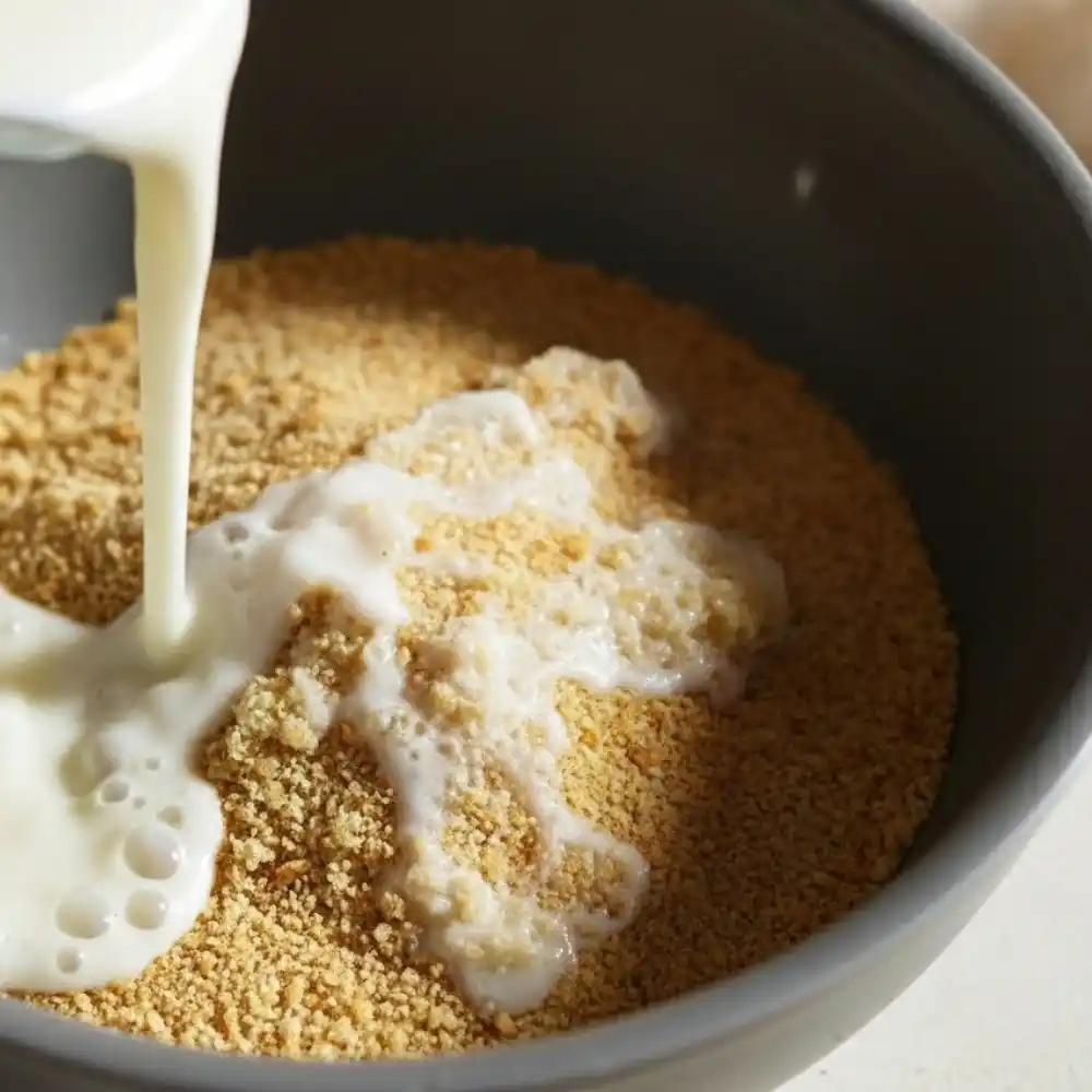 Milk being poured into a bowl of breadcrumbs to create a binder for the Kobe beef meatloaf mixture.