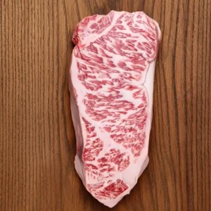 Fresh uncooked Kobe beef steak with rich marbling on a wooden board.