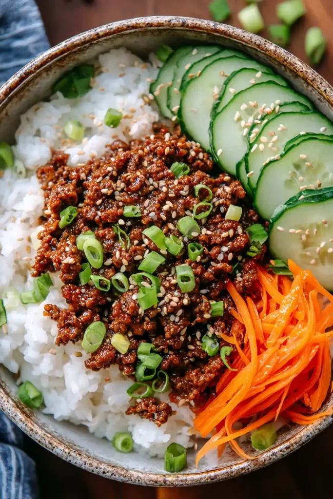 Classic Korean beef bowl recipe served with rice, seasoned beef, cucumbers, carrots, and sesame seeds