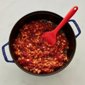 Tomato paste and onions cooking together in a Dutch oven as the base for Marry Me Chicken Soup.