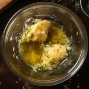Garlic butter mixture with herbs in a glass bowl for slow cooker beef bites and potatoes