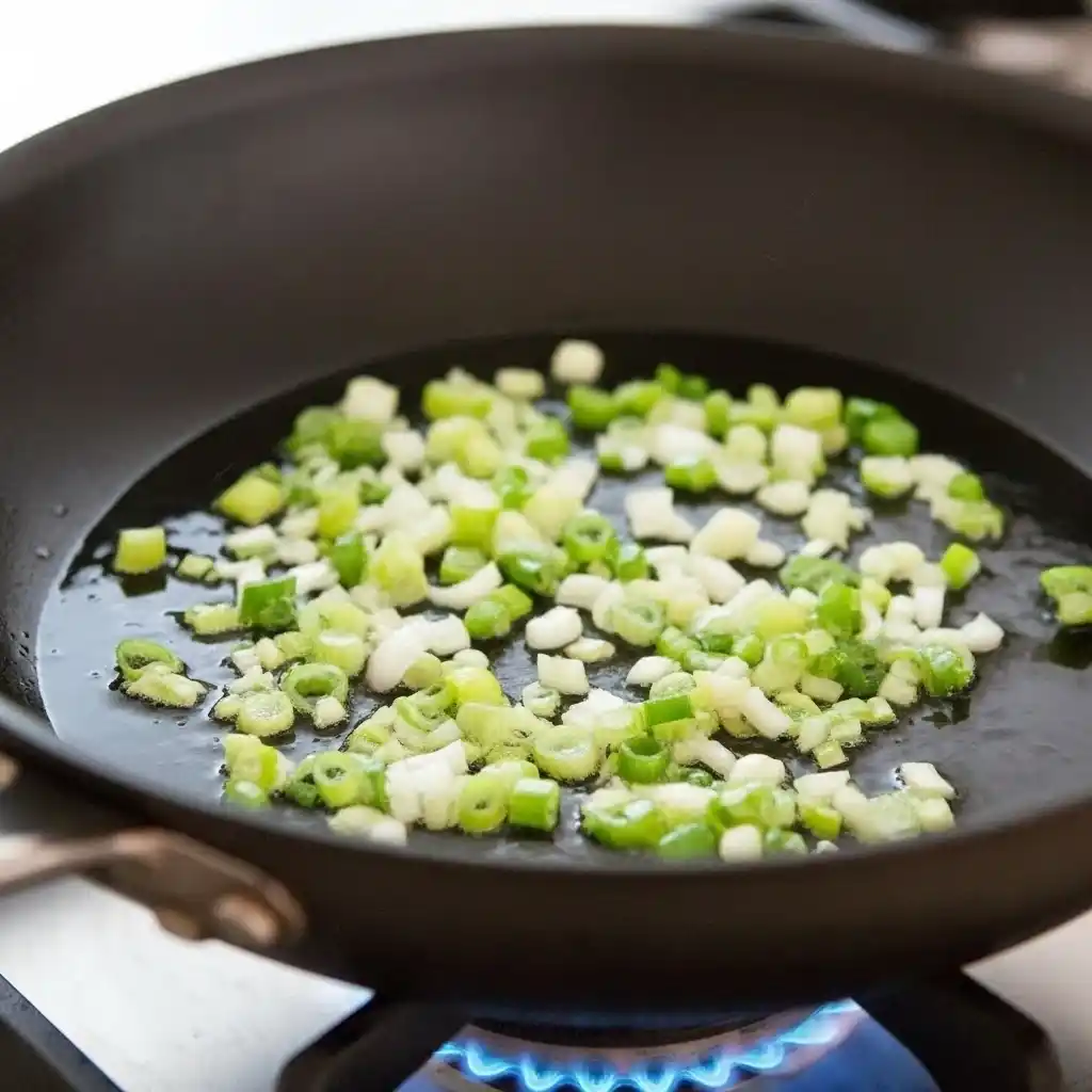 Green onions and garlic sizzling in oil for shrimp fried rice recipe