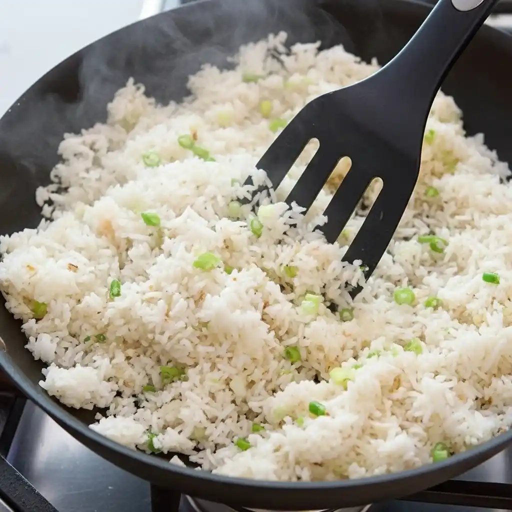 Day-old rice frying in wok with green onions for shrimp fried rice recipe
