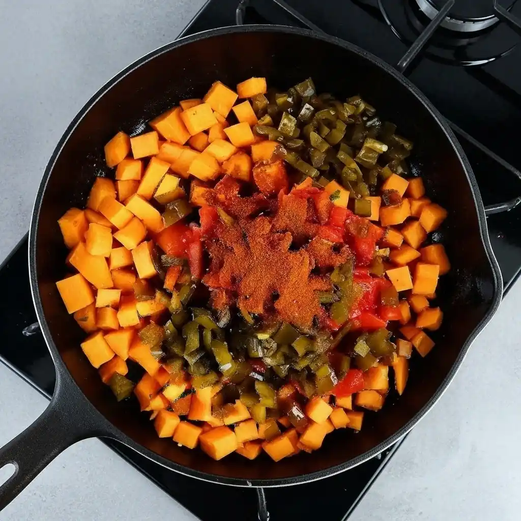 adding sweet potatoes and tomatoes to skillet with beef