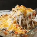 Golden cheesy hamburger rice casserole baked with ground beef, rice, carrots, and melted cheese in a white dish.