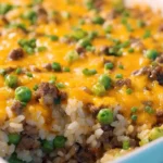 Cheesy Ranch Ground Beef and Rice Casserole topped with melted cheddar and peas