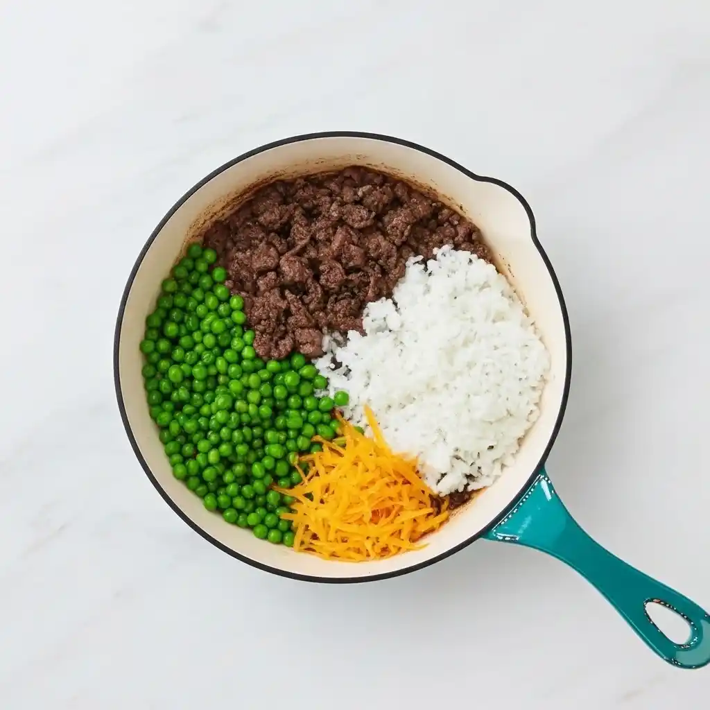 Layers of ground beef, rice, peas, and melted cheddar cheese in ranch casserole