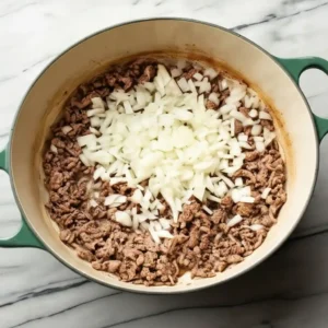 Browning ground beef with chopped onion for tomato cream orzo