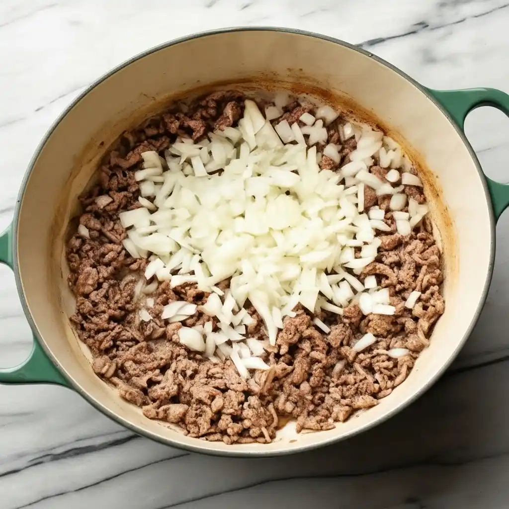 Browning ground beef with chopped onion for tomato cream orzo