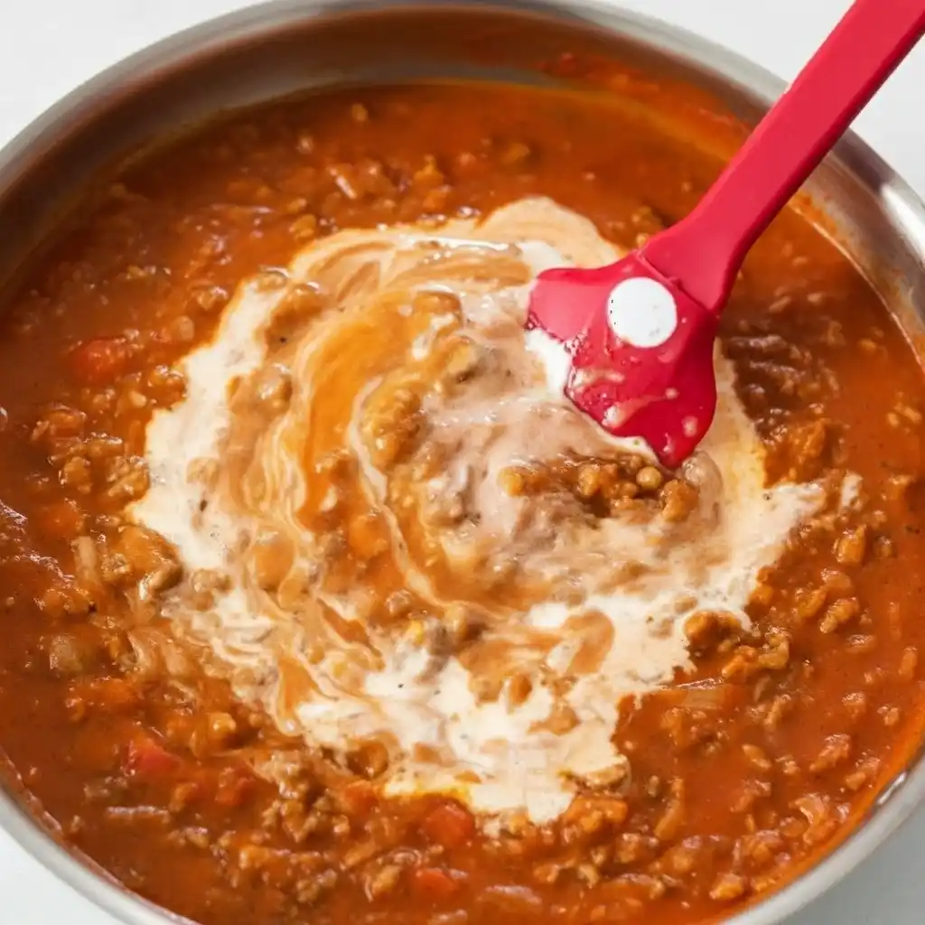 Stirring cream into tomato beef sauce