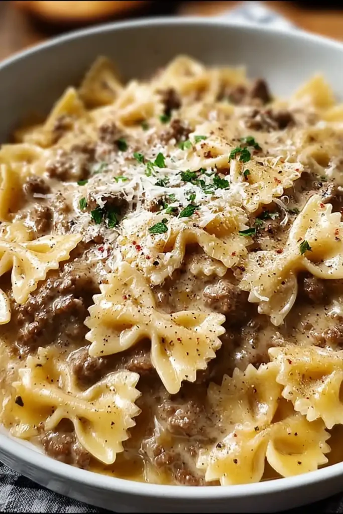Creamy Parmesan Garlic Beef Bowtie Pasta served in a white bowl topped with Parmesan and parsley