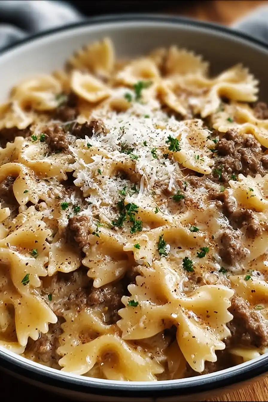 Bowl of creamy beef and bowtie pasta garnished with fresh parsley and Parmesan