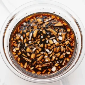 Bowl of brown sugar, soy sauce, garlic, and lemon being whisked together