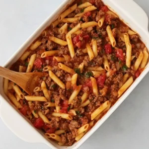 mixing pasta with ground beef sauce in baking dish