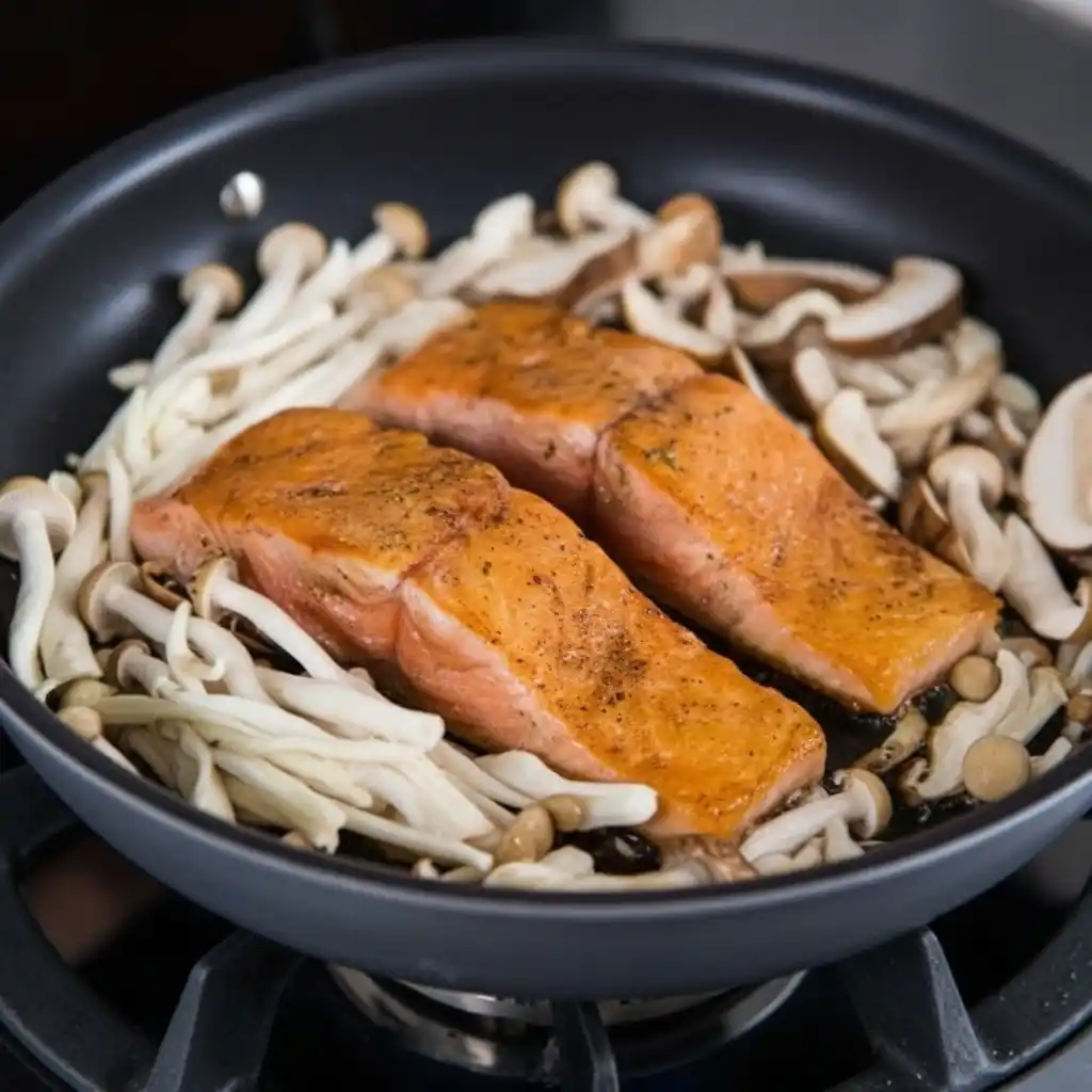 salmon fillets pan searing with mushrooms in skillet