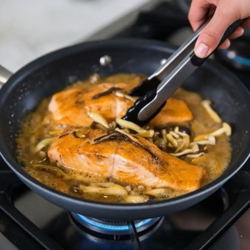 salmon fillets cooking in miso butter glaze with mushrooms