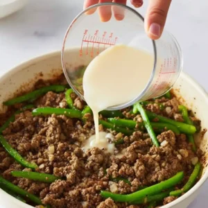 Pouring cornstarch beef broth mixture into ground beef and peppers skillet