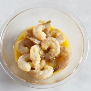 Raw shrimp coated in garlic butter mixture before air frying