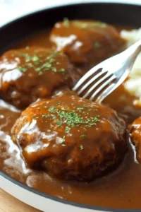Salisbury steak served with brown gravy on a white plate