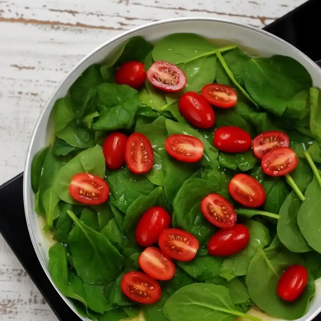 Cooking spinach and cherry tomatoes in skillet