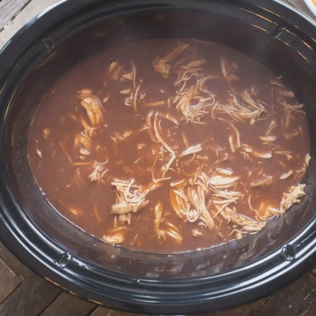 Chicken Enchilada Crockpot Casserole shredded chicken simmering in red enchilada sauce