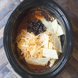 Chicken Enchilada Crockpot Casserole step with tortilla strips and cheese