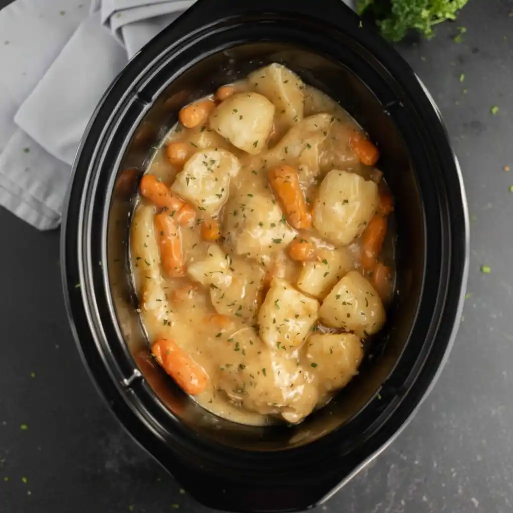 Finished creamy ranch chicken crock pot with a wooden spoon.