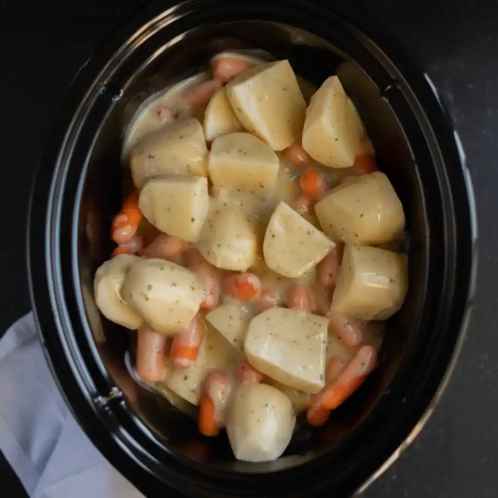 Potatoes and carrots layered with creamy ranch sauce in a slow cooker.
