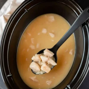 Chicken and broth mixture in crock pot for Crock Pot Chicken and Rice Recipe