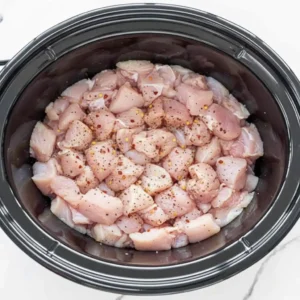 Seasoned chicken in slow cooker for Crockpot Creamy Tuscan Chicken Orzo