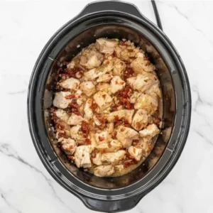 Chicken simmering in broth and tomato sauce for creamy Tuscan orzo