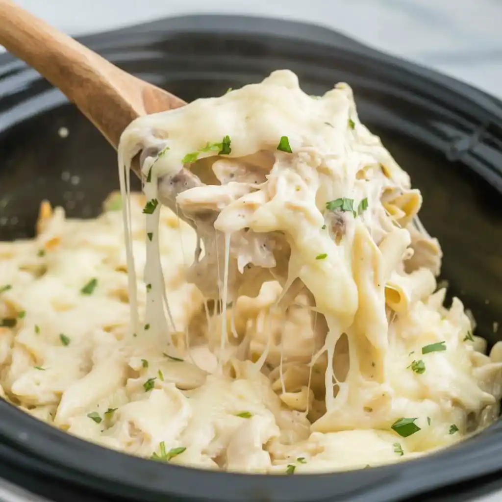 cheese pull from creamy crockpot chicken alfredo bake