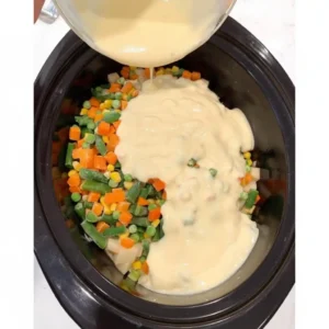 Pouring cream of chicken soup over vegetables in crockpot