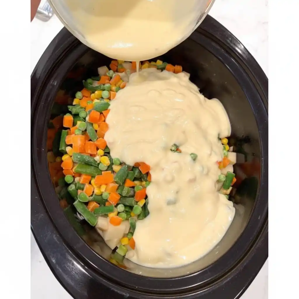 Pouring cream of chicken soup over vegetables in crockpot