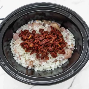 Chicken and sun-dried tomatoes layered in crockpot for Tuscan chicken