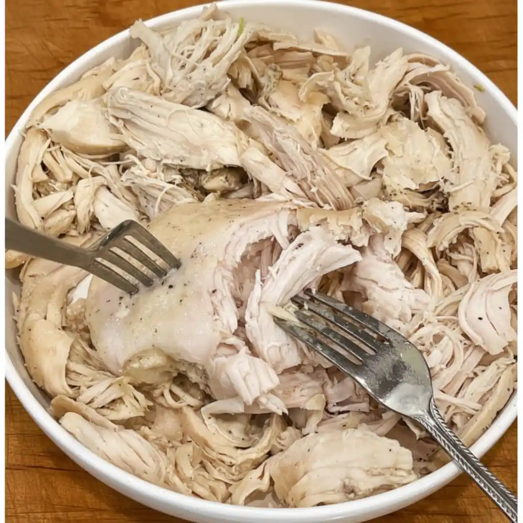 Shredding cooked chicken with forks for crockpot pot pie