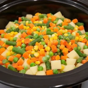 Slow cooker filled with chicken pot pie mixture and vegetables