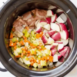 Layering chicken, potatoes, and vegetables in a slow cooker for creamy stew