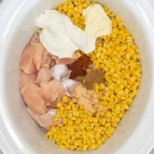 Raw chicken corn and spices in slow cooker